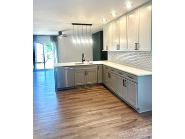 Modern kitchen with stainless steel appliances, white cabinets, and hardwood flooring at 5234 Bellflower Ln, Charlotte, NC 28227