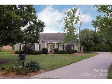 Charming single-story home with a well-manicured lawn, lovely landscaping and a curved driveway at 8829 Gelligum Dr, Charlotte, NC 28277