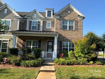 Charming brick two-story home with a welcoming front porch and well-manicured landscaping at 11608 Founders Park Ln, Pineville, NC 28134
