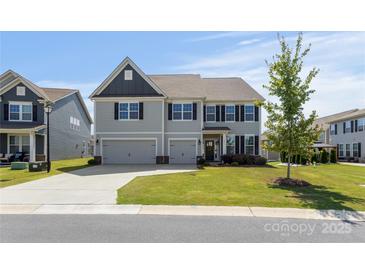 Inviting two-story home with a well-manicured lawn, a two car garage, and classic architectural details at 2097 Saddlebred Dr, Iron Station, NC 28080