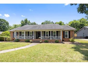 Charming single-story brick home featuring a welcoming front porch with decorative railings and a well-manicured lawn at 5006 Crooked Oak Ln, Charlotte, NC 28226