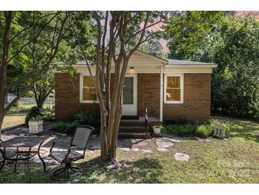 Charming brick home featuring a cozy porch, mature trees, and a well-maintained front yard at 6616 Woodlawn Ln, Indian Trail, NC 28079
