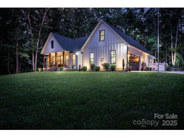 Stunning two-story home featuring a lush green lawn, inviting front porch, and attached garage with a well-lit exterior at 2418 Shuford Rd, Lincolnton, NC 28092