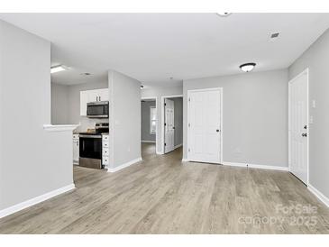 Bright living room featuring sleek flooring and modern white kitchen appliances at 3853 Carl Parmer Dr, Harrisburg, NC 28075
