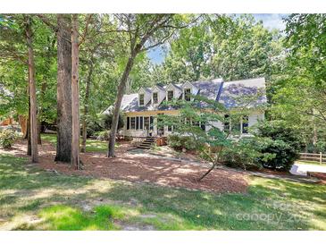 Charming home with dormer windows nestled amongst mature trees and beautiful landscaping at 8500 Peyton Randolph Dr, Charlotte, NC 28277