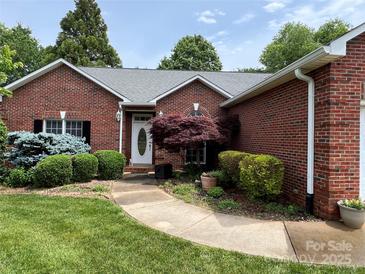 Charming brick home featuring a well-manicured lawn, lush landscaping, and a welcoming front entrance at 2225 Water Oak Ln, Gastonia, NC 28056