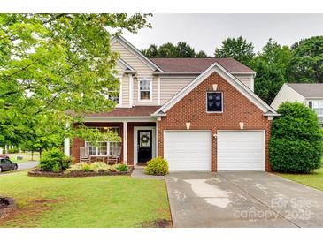 Charming two-story home featuring a brick facade, attached garage, and meticulously landscaped front yard at 2103 Cantata Ct, Matthews, NC 28105
