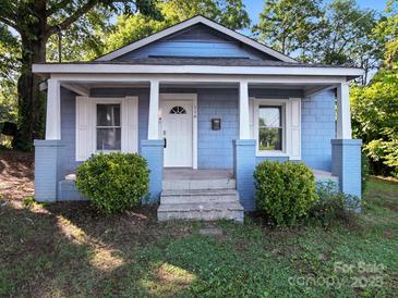 Charming light blue home featuring a cozy front porch with white columns and trimmed windows with a landscaped yard at 116 Honeywood Ave, Charlotte, NC 28216