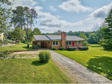 Charming brick home with a metal roof, a red door, and a spacious front yard at 7753 Caswell Rd, Stanley, NC 28164