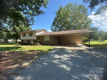 Charming split-level home with a brick facade and covered carport, surrounded by mature trees and a gravel driveway at 12003 Old Beatty Ford Rd, Rockwell, NC 28138