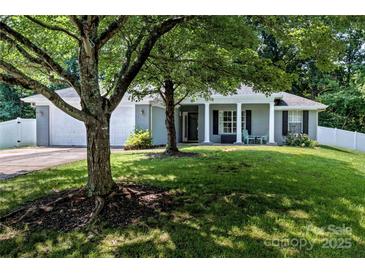 Charming one-story home with a well-manicured lawn and inviting front porch with white columns and mature trees at 13517 Silver King Ct, Huntersville, NC 28078