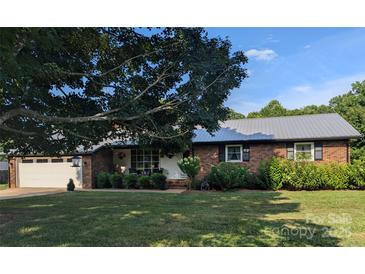 Charming brick home featuring a metal roof, well-manicured lawn, and an attached two-car garage at 3080 Shue Rd, Salisbury, NC 28147