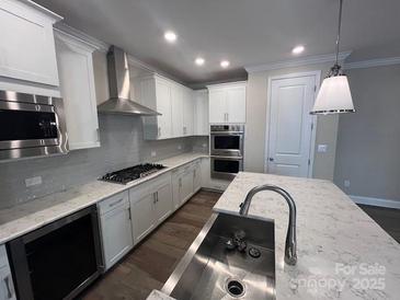 New kitchen features white cabinets, stainless steel appliances and large island with a sink and quartz countertop at 707 Marion Dr, Matthews, NC 28105