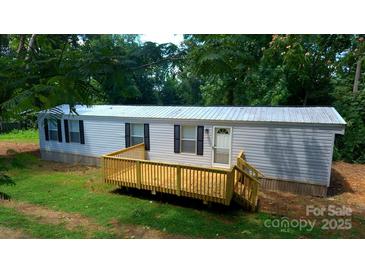 Exterior of home featuring an elevated front deck, neutral siding, black shutters, and lush greenery around property at , Salisbury, NC 28146