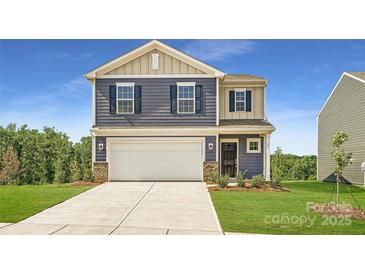 Charming two-story home featuring a two-car garage, manicured lawn, and classic architectural details at 143 Astor St, Troutman, NC 28166