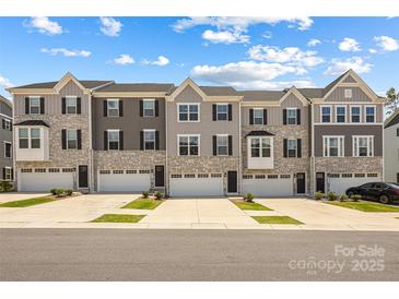 Stylish townhome exteriors showcasing stone accents, complementary siding, and individual garages under a bright sky at 2040 Dornoch Rd, Tega Cay, SC 29708