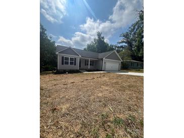Charming one-story home featuring gray siding, black shutters, and an attached garage, surrounded by a partially unkempt yard at 268 Hatley Ne Cir, Concord, NC 28025