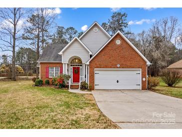 Charming brick home featuring a well-manicured lawn, a red front door with festive holiday wreath at 105 Whimbrel Ln, Mooresville, NC 28117