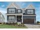 Two-story home with dark blue siding, white trim, stone accents, a covered front porch, and a two-car garage at 11330 James Coy Rd # Covington, Davidson, NC 28036