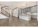 Open-concept kitchen with gray cabinets, large island, hardwood floors, and staircase at 8159 Fairview Rd, Charlotte, NC 28226