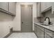 Well-organized laundry area with gray cabinets, marble counters, and sink at 8159 Fairview Rd, Charlotte, NC 28226
