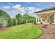 Expansive backyard featuring a well-maintained lawn, tasteful landscaping, and a covered patio with a cozy fireplace at 8163 Fairview Rd, Charlotte, NC 28226