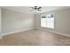A bedroom features wood flooring, neutral paint, a ceiling fan, and a window for natural light at 8163 Fairview Rd, Charlotte, NC 28226