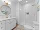 Bright bathroom features a glass enclosed shower, round mirror, and white cabinets at 4016 Nettie Ct, Charlotte, NC 28211