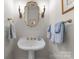 Elegant powder room with a pedestal sink, gold fixtures, ornate mirror, and sconces at 4016 Nettie Ct, Charlotte, NC 28211