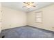 This bedroom features neutral paint, a ceiling fan, a window with blinds, and blue carpeting at 1302 Hickory Nut Ln, Lincolnton, NC 28092