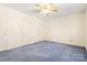 This bedroom features neutral paint, a ceiling fan, multiple doors, and blue carpeting at 1302 Hickory Nut Ln, Lincolnton, NC 28092
