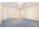 This bedroom features neutral paint, a ceiling fan, three doors, and blue carpeting at 1302 Hickory Nut Ln, Lincolnton, NC 28092