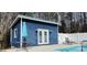 Stylish blue pool house with white trim, French doors, outdoor table, and a refreshing swimming pool at 12505 Old Beatty Ford Rd, Rockwell, NC 28138