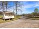 Welcoming golf course entrance featuring a sign, paved road, lush trees, and partial pond view at 120-B Deer Brook Dr, Shelby, NC 28150