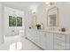 Bathroom with a double vanity, soaking tub, and white cabinets with gold hardware at 4142 Pineview Rd, Charlotte, NC 28211