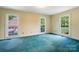 A bedroom with three windows features blue carpet, neutral-colored walls, and a garage view at 218 Fairway Dr, Shelby, NC 28150