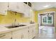 An eat-in kitchen with stainless steel sinks looks toward a sunroom with exposed brick at 218 Fairway Dr, Shelby, NC 28150