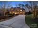 Beautiful brick home with a large driveway surrounded by mature trees at dusk at 2012 Tomshire Dr, Gastonia, NC 28056