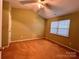A bright bedroom is shown with neutral walls, carpet, and a window at 10875 Holly Ridge Blvd, Charlotte, NC 28216