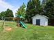 Landscaped backyard featuring a play set and shed for outdoor activities at 5535 Whispering Wind Ln, Indian Trail, NC 28079