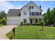 Charming two-story home features a well-manicured lawn, a classic white exterior, and inviting front porch at 5535 Whispering Wind Ln, Indian Trail, NC 28079