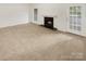 Cozy living room with a fireplace and a door to the backyard, featuring neutral carpeting at 6003 Treetop Ct, Charlotte, NC 28212