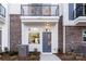 An exterior view shows the townhome with a brick bottom, gray door, balcony and black railings at 1409 Collier Walk Aly # Csw0104, Charlotte, NC 28205