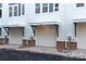 An exterior view shows the garages of the townhomes, with white doors, brick bottoms, and white siding at 1409 Collier Walk Aly # Csw0104, Charlotte, NC 28205