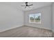 A clean, bright bedroom with neutral walls, ceiling fan, gray floors, and a window offering plenty of natural light at 6122 Lowder Rd, Salisbury, NC 28147