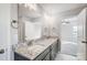 A bathroom featuring double sinks, granite counters, large mirror, and doorway to the bedroom at 11507 Valley Oaks Ln, Stanfield, NC 28163