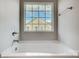 A simple white bathtub is situated below a window in the bathroom, offering natural light at 11507 Valley Oaks Ln, Stanfield, NC 28163
