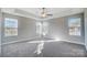 A spacious bedroom featuring plush carpeting, natural light from three windows, and a modern ceiling fan at 11507 Valley Oaks Ln, Stanfield, NC 28163