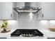 Close-up of stovetop with tile backsplash and stainless steel hood at 2016 Cedar Falls Dr # 7, Waxhaw, NC 28173