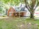 Brick house with covered porch, landscaping, and large tree at 5237 Nc Highway 90 E Hwy, Hiddenite, NC 28636